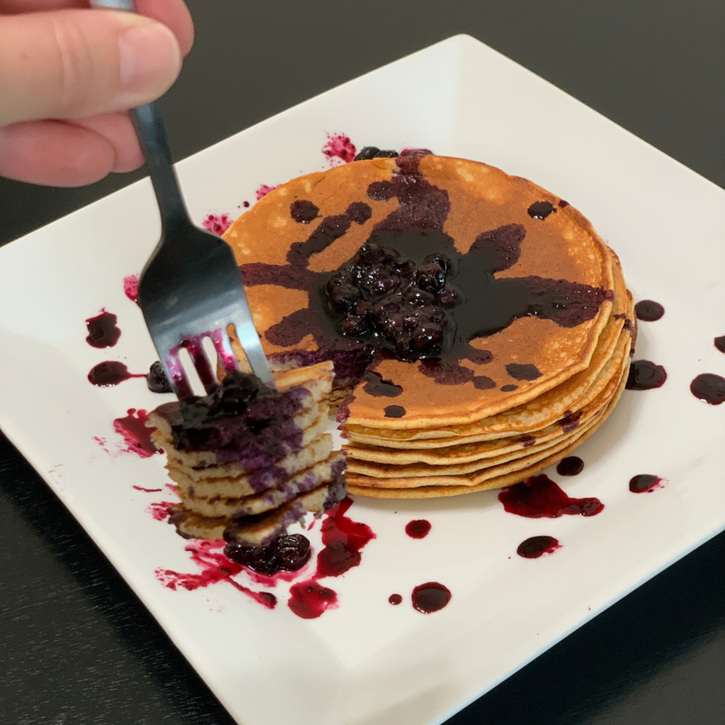 A bite of Protein Pancakes With Fresh Blueberry Syrup.